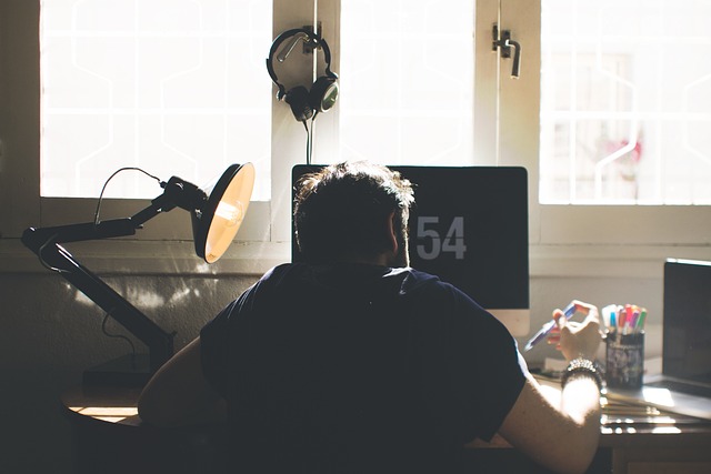 person working from home with golden retriever resting nearby laptop and notebook on desk