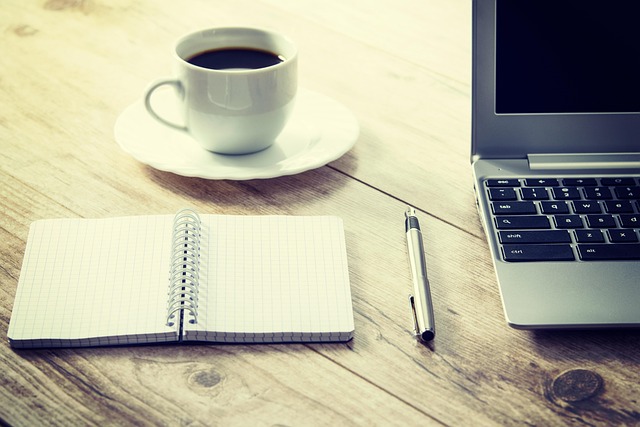 person working from home with cat resting on desk near laptop and notebook